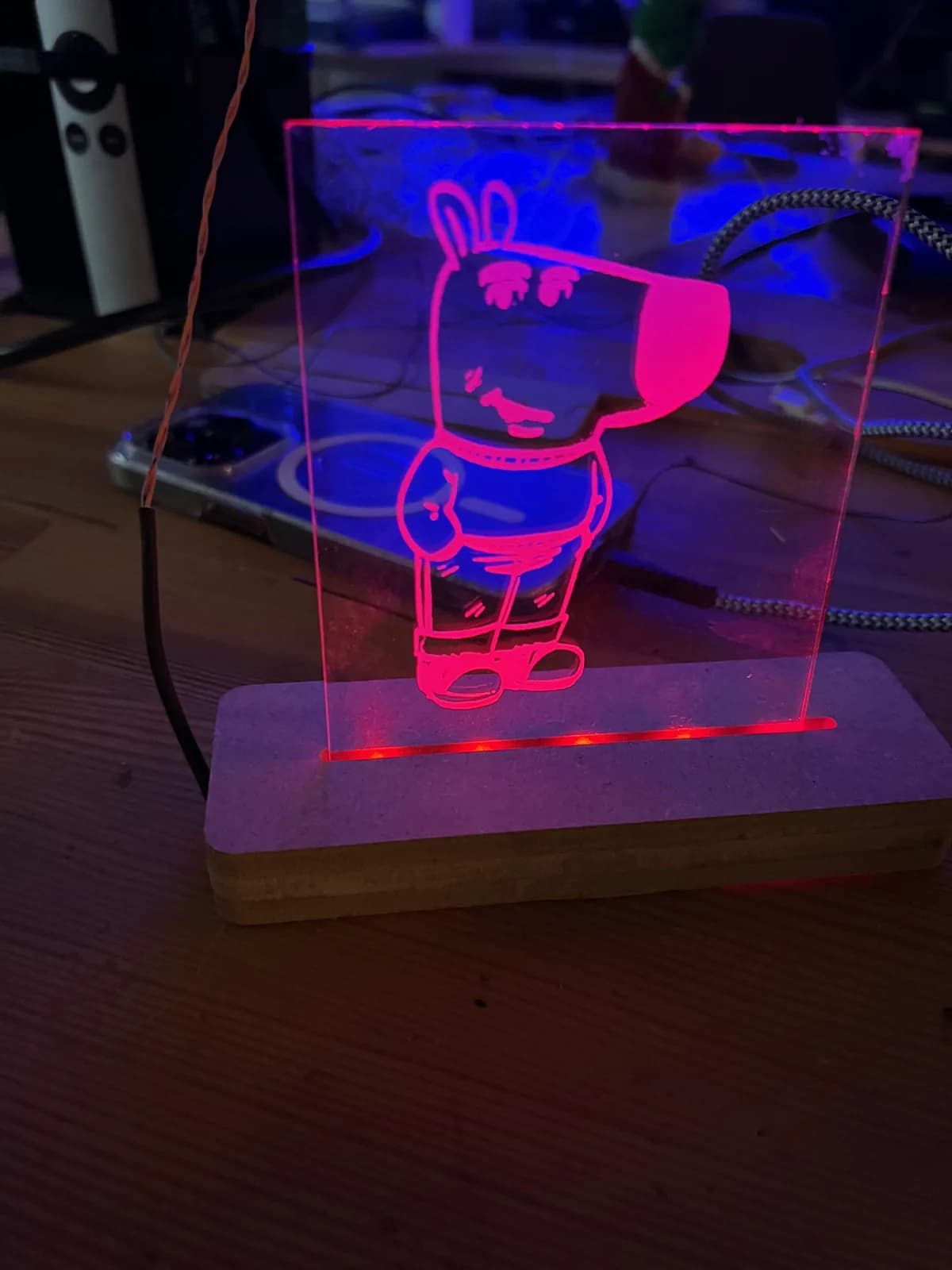 En tegnet figur lyser rosa i en pleksiglasslampe